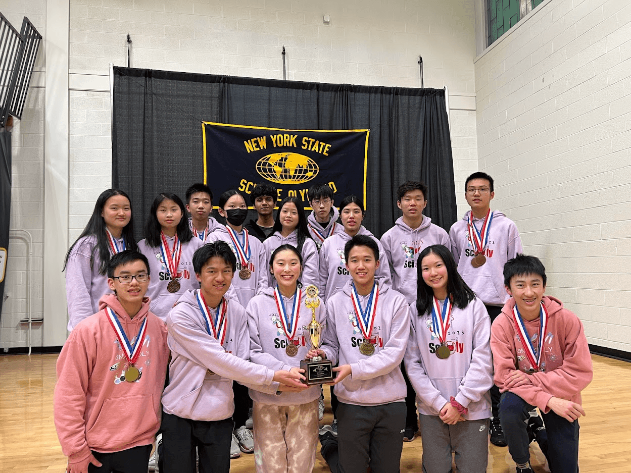 Team members with medals holding a trophy in front of the New York State Science Olympiad banner