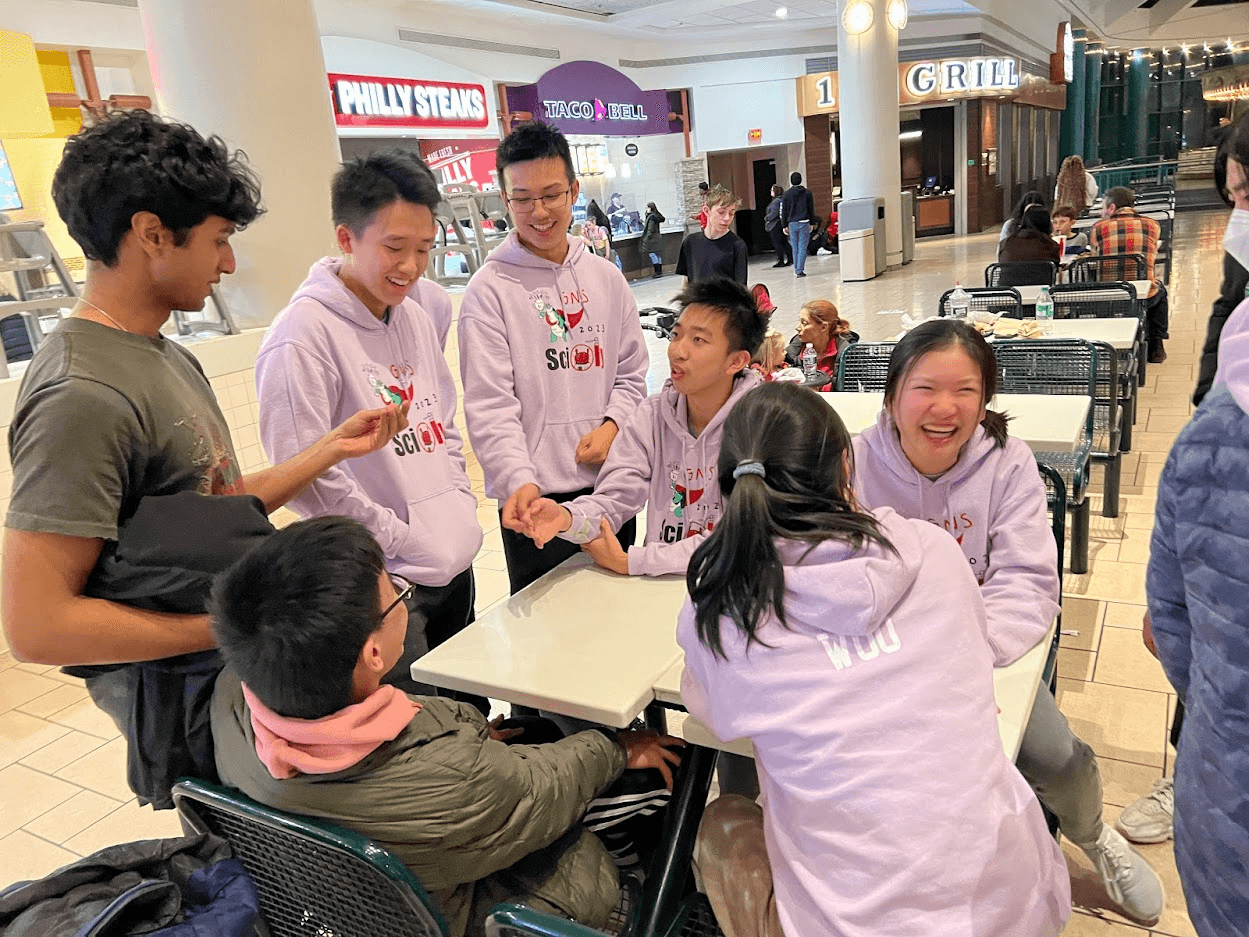 Members laughing around a food court table between events