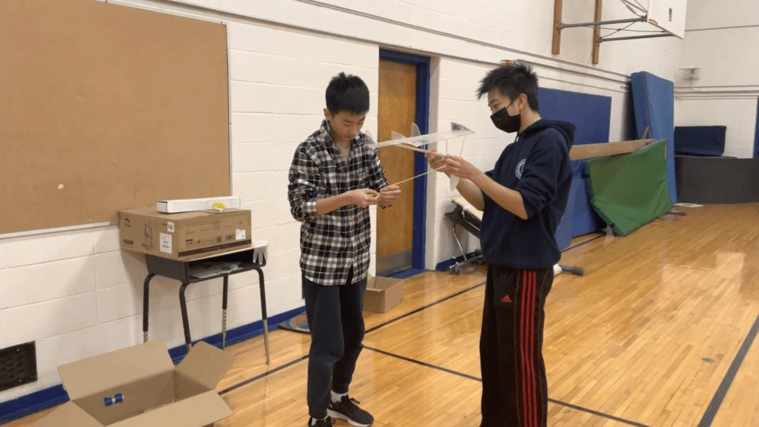 Two members testing a device in the school gym