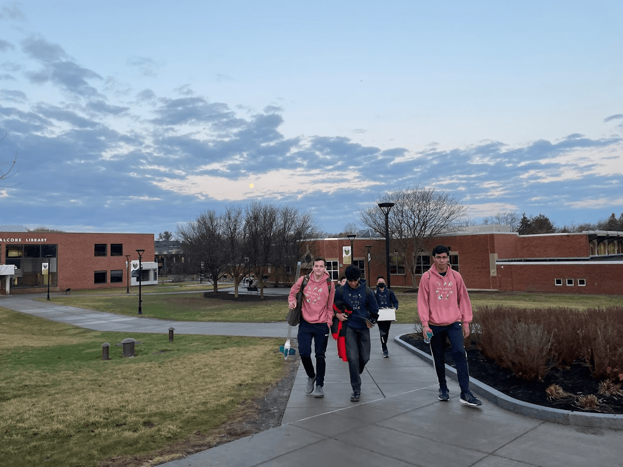 Members walking across a college campus at dusk